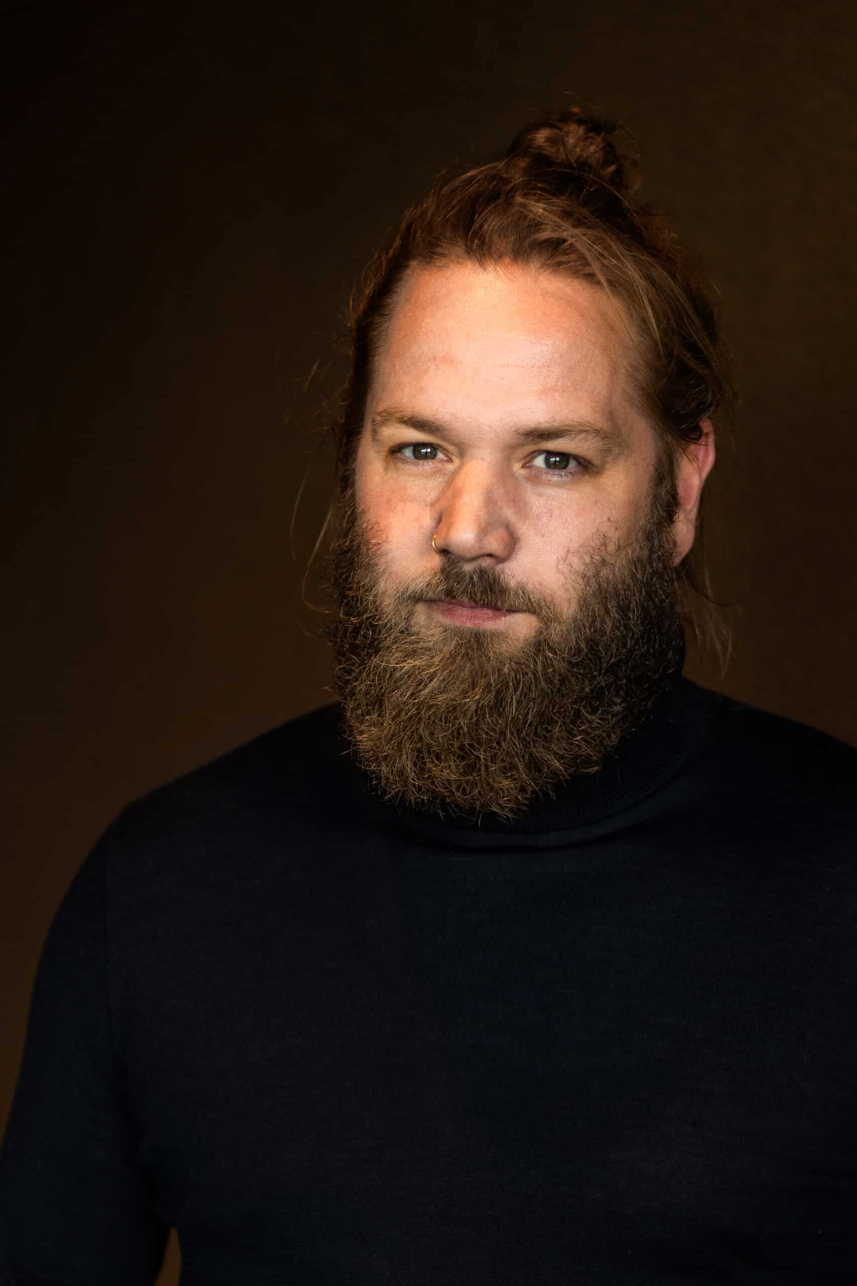 Portret van een man met baard en knotje.