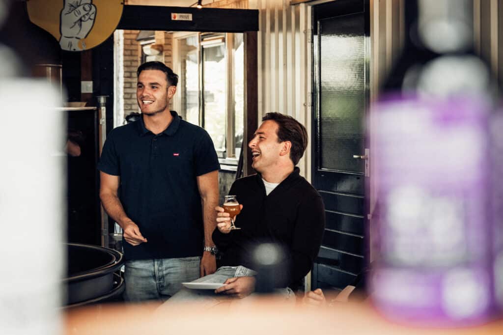 Twee mannen lachen en drinken in de bar.