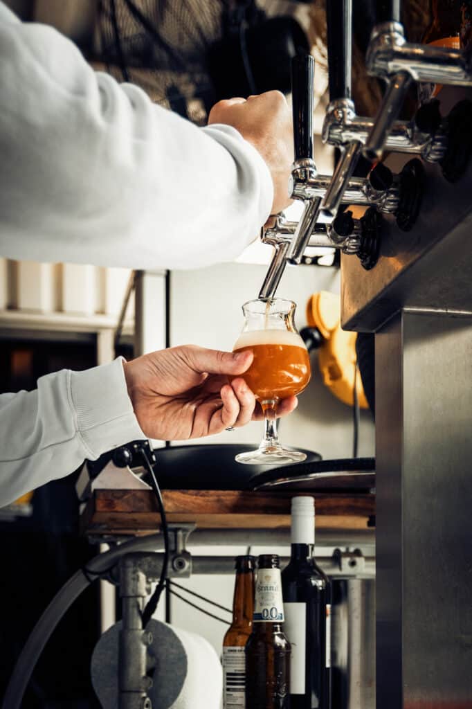 Persoon tapt vers bier in glas bij tapkraan.