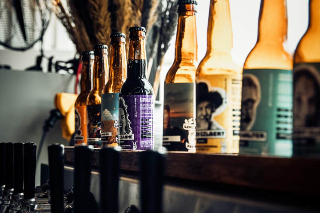 Verschillende bierflesjes op een rij op de bar.