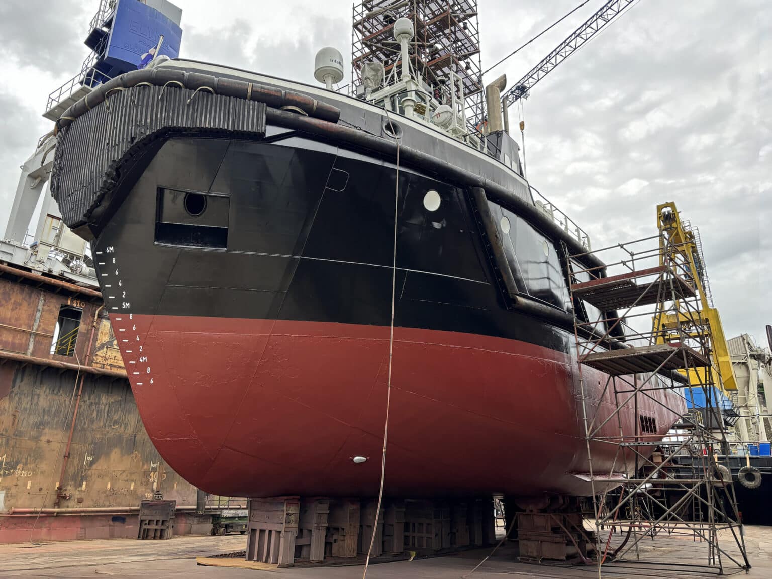 Groot schip in droogdok met steigers ernaast.