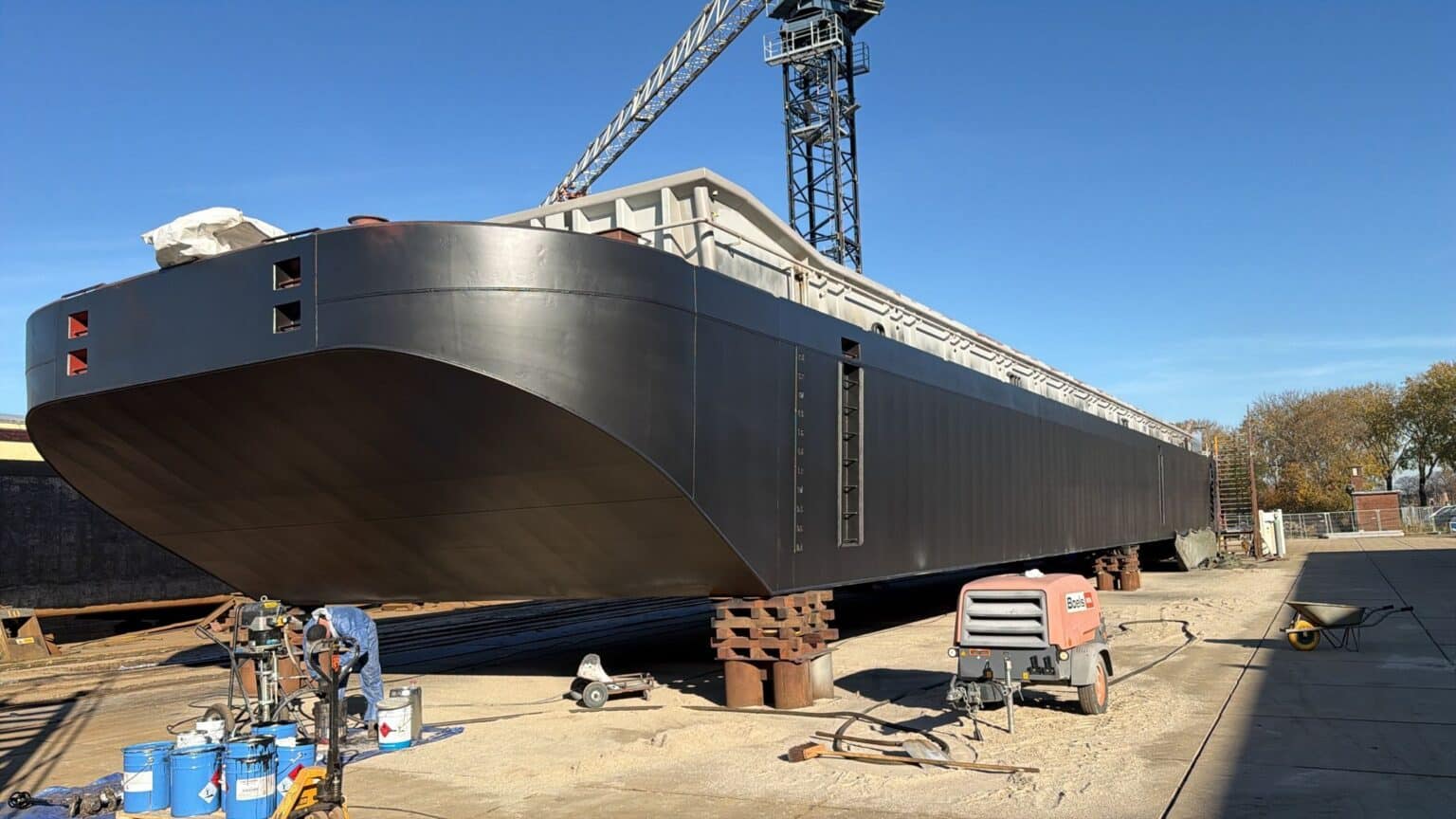Schip in aanbouw op scheepswerf bij heldere lucht.